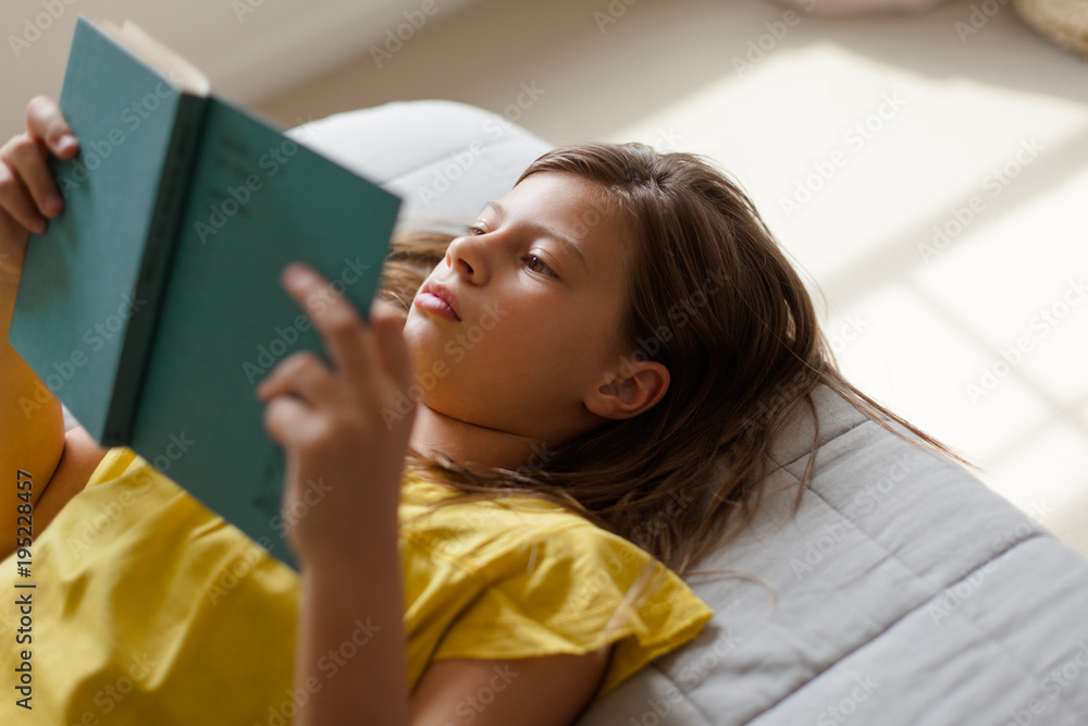 Preteen girl quietly reading a book at home Stock Photo | Adobe Stock