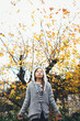 © Robert Lang Photography/Stocksy - A girl standing with eyes closed against autumn tree