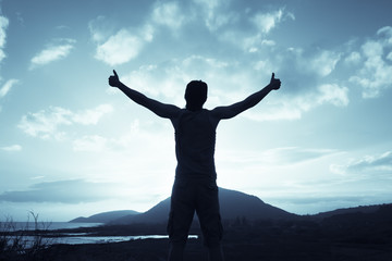 Positive feelings. Man standing on a mountain feeling happy, and free. Thumbs up!