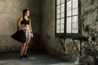 Strong brunette woman resting after boxing workout holding sport bag.