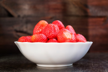 Strawberry in plate on brown background