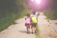 Two Little Children Boy And Girl Walking On A Road