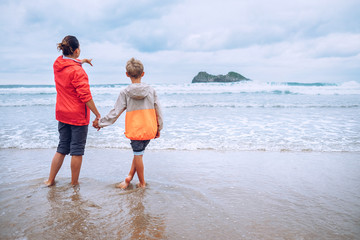 Wall Mural - Mother and son walk on coast line after rain