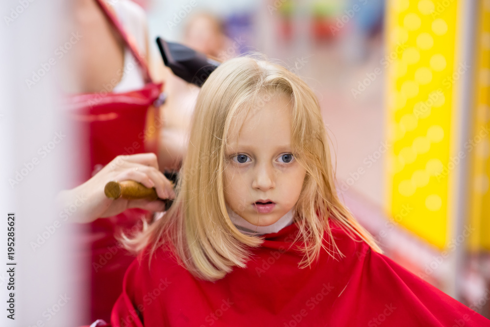 little girl smiles and does a haircut in a beauty salon. Stock Photo ...