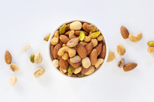 Healthy Food And Snack : Mixed Nuts In White Ceramic Bowl On White Background From Above, Pistachios, Almonds, Hazelnuts And Cashew.