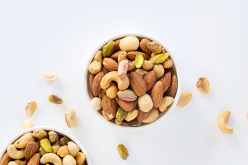 Sticker - Healthy food and snack : mixed nuts in white ceramic bowl on white background from above, pistachios, almonds, hazelnuts and cashew.