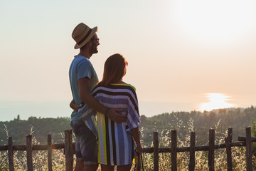 Wall Mural - Young couple in love enjoying sunset over the sea