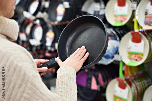 Fotografía Woman chooses frying pan in crockery store