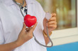 © krumanop - Doctor hand hold red heart shape and stethoscope hang in neck. Research in laboratory for heart disease. Healthy and science concept. Soft focus and blur green nature background.