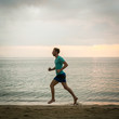 © Kzenon - Full length side view of an athletic young man running on the beach during cardio workout session in summer vacation in Indonesia