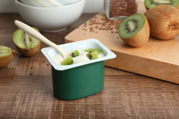 Canvas Print - Plastic cup of yummy kiwi yogurt on wooden table