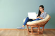 © Africa Studio - Young Asian woman using laptop in lounge chair, indoors