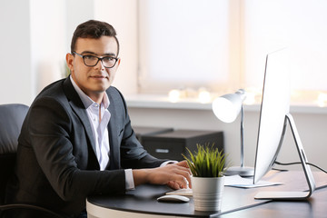 Wall Mural - Young man in office wear working with computer at table