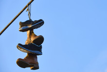 Old Shoes Hanging On Electrical Wire Against A Sky. Shoe Tossing
