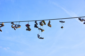 Old Shoes hanging on electrical wire against a sky. Shoe tossing
