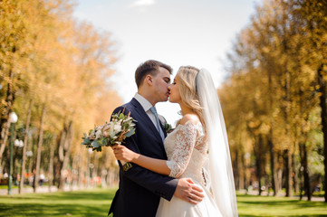 Wall Mural - Bride and bridegroom kissing in the park