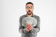 © Drobot Dean - Shocked businessman holding money.