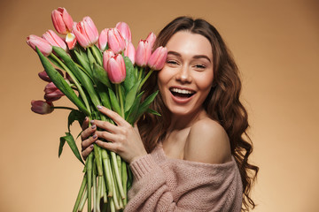 Sticker - Cheerful young lady with long brown hair being excited to get bouquet of pink tulips on women's day, isolated over beige background