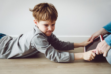 computer addiction- father taking touch pad from angry child