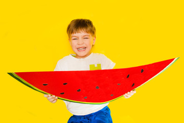 Funny kid with watermelon from a cardboard on a yellow background. healthy food.