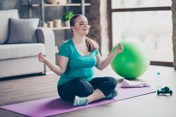 Young woman meditating on yoga mat at home