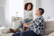 Happy child. Nice exuberant curly-haired girl smiling and sitting on the couch and talking with her father and they looking at each other
