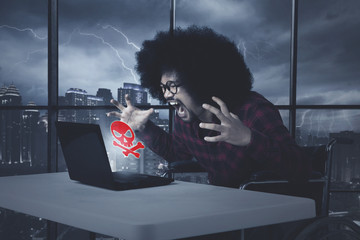 Angry african american man with damaged laptop