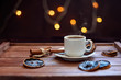 Чашка кофе с сушеными дольками лимона и палочками корицы на деревянном коричневом фоне с огнями гирлянды