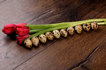 Spring tulips and quail eggs on a wooden background