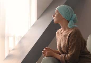 young woman with cancer in headscarf indoors