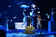Young actors scatter sheets of paper on stage