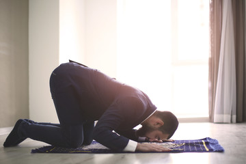 Wall Mural - Young Muslim man praying, indoors