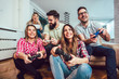 © Mediteraneo - Group of friends play video games together at home, having fun.