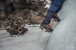 Climber on a frozen waterfall. Crampons close-up on his feet ice climber