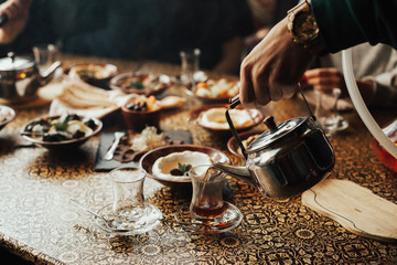 Young happy company of people is eating lebanon food and smokinh shisha. Lebanon cuisine. Traditional meze lunch