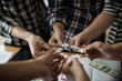 © xreflex - Hands group of business people assembling jigsaw puzzle white. Below is the graph paper business documents placed on a wooden table in the meeting room.