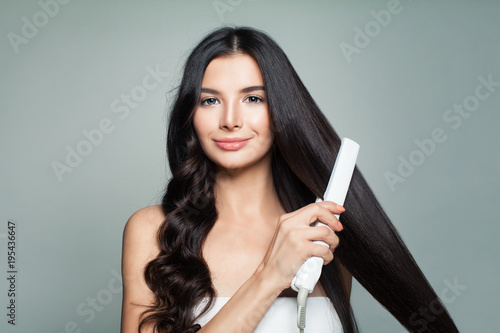 Cuadros en Lienzo Attractive Woman with Curly Hair and Long Straight Hair Using Hair Straightener