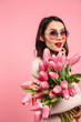 © Drobot Dean - Photo of attractive woman with long dark hair in fashionable sunglasses posing on camera with lots of spring flowers, isolated over pink background