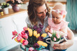 Happy mother and baby making decoration with bouquet of tulips