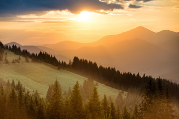 Wall Mural - beautiful dramatic sunset in the mountains. landscape with sun shining through orange clouds