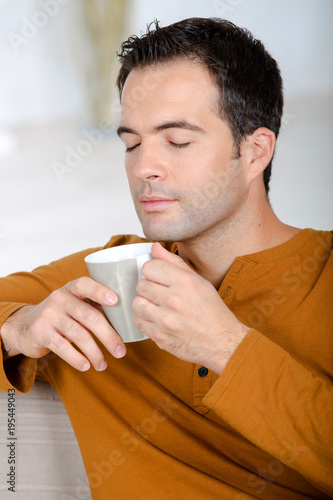 Plakat młody człowiek, ciesząc się herbaty z zamkniętymi oczami