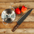 © kuzovkov - The metal saucepan, knife and pepper lie on a wooden table.