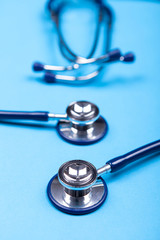 Close up image of two stethoscopes lying on blue background