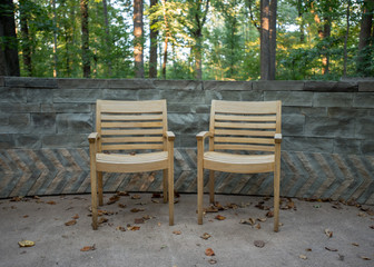 Two Wooden Arm Chairs Against Stone Wall