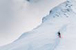 Two skiers in multi-colored suits climb a high snow mountain