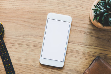 blank smart phone decorate with stationary items on wooden table, note book;clippers,airplane on wooden working desk.flat lay,top view