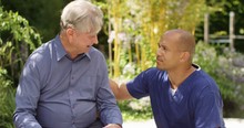4K Caring Nurse Offering Comfort To Senior Man Upset In Retirement Home Garden. Slow Motion