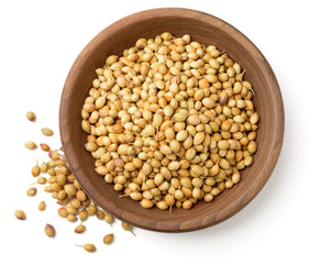 Sticker - dried coriander seeds in the wooden plate, isolated on white, top view