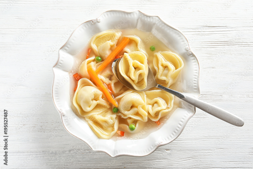 Tasty broth with dumplings on wooden table