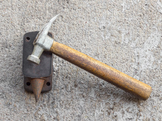 Old small hammer and miniature anvil with concrete background